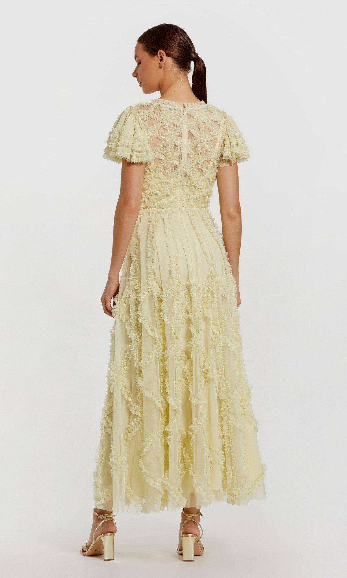 A woman wearing the Long Formal Dress: Mac Duggal 8282—an ankle-length, pale yellow lace dress with ruffle details—stands facing away from the camera in heeled sandals.